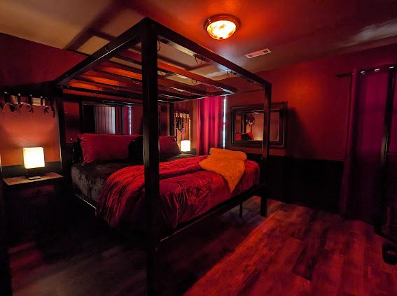 Steel four-poster bondage bed with overhead anchor points in the Bondage Suite