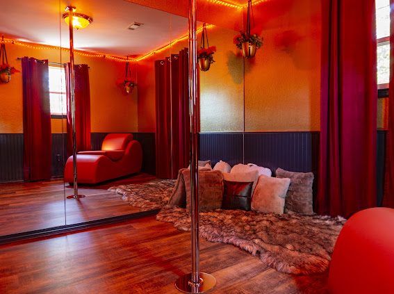 The Pole Lounge with floor-to-ceiling mirrors, performance pole and red chaise