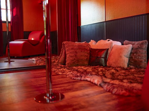 Floor pillows and faux fur rug beside the pole in the Pole Lounge